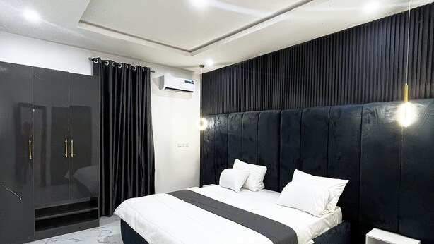 Un dormitorio moderno con una cama grande, un armario y una mesita de noche.