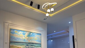 Una sala de estar moderna con un sofá seccional color beige, una mesa redonda de centro y un cuadro con una escena marina.