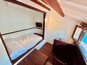 A bunk bed with a TV and a small table, wooden flooring, and a window with a view. - Pousada e Restaurante do Paulo (Jijoca de Jericoacoara)