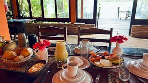 A breakfast table set with various dishes, a pitcher, and a vase with flowers. - Pousada e Restaurante do Paulo (Jijoca de Jericoacoara)