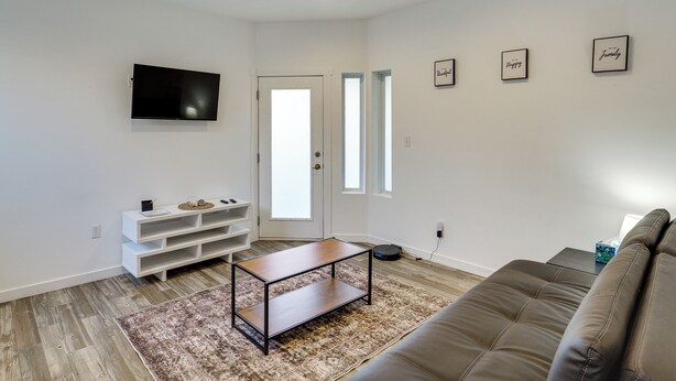 Een moderne woonkamer met een bruine leren bank, een houten salontafel en een witte dressoarkast.