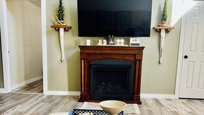 A living room with a fireplace, a television, and a decorative mantel.