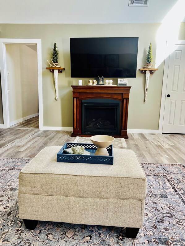 Una sala de estar con chimenea, televisión y un repisa decorativa.