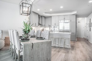 A modern kitchen with grey cabinets, a central island, and stainless steel appliances. - Coastal Three Bedroom Penthouse Offering Breathtaking Bayside Views. Complimentary Boat Slip! (Orange Beach)