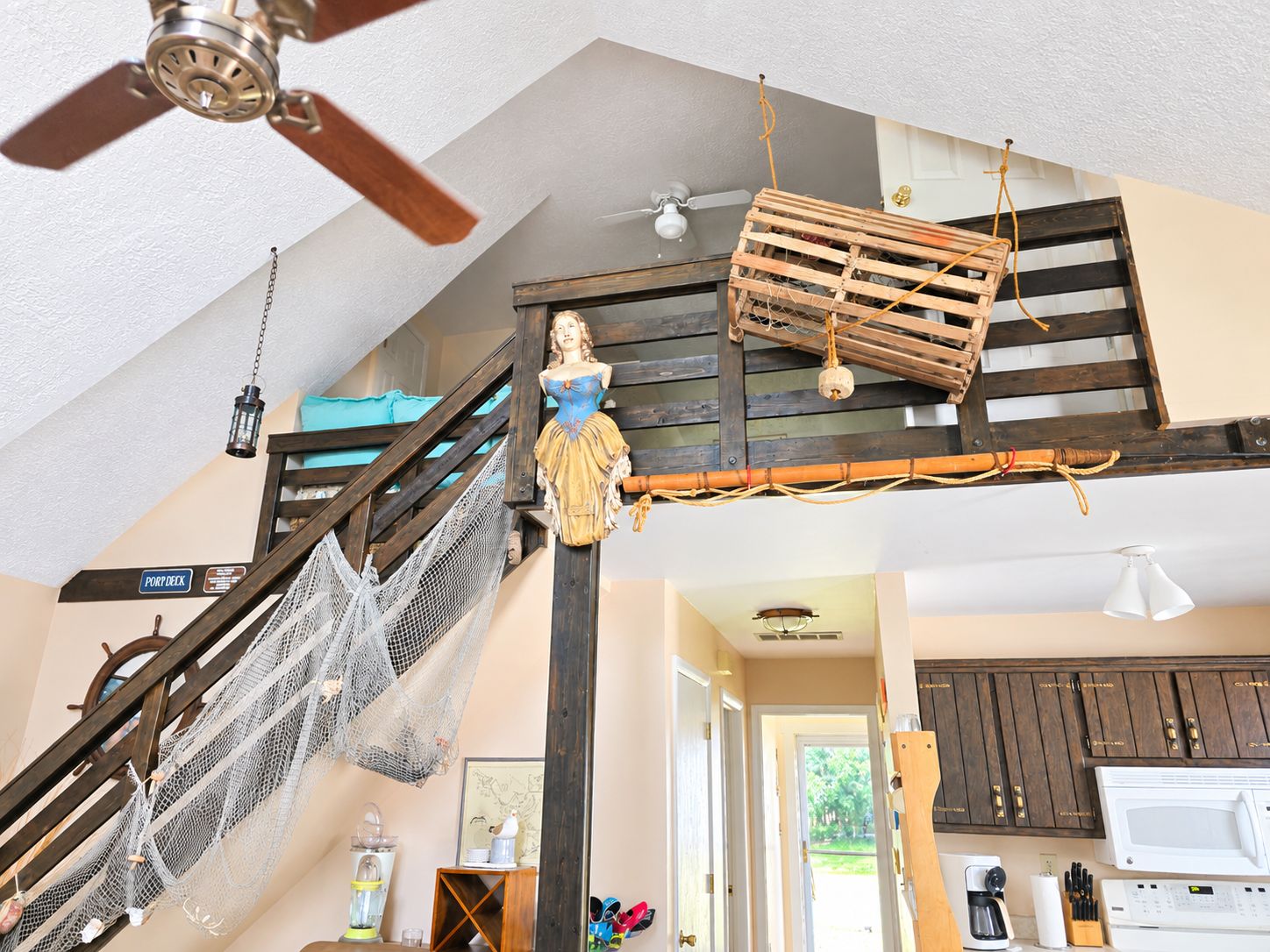 Ein mehrstöckiges Interieur mit Treppe, Deckenventilator und Küchenzeile.