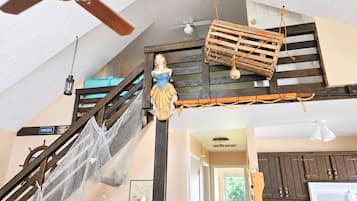 Ein mehrstöckiges Interieur mit Treppe, Deckenventilator und Küchenzeile.