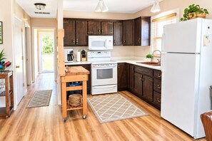 A kitchen with dark wooden cabinets, a white refrigerator, a microwave, an oven, and a sink.