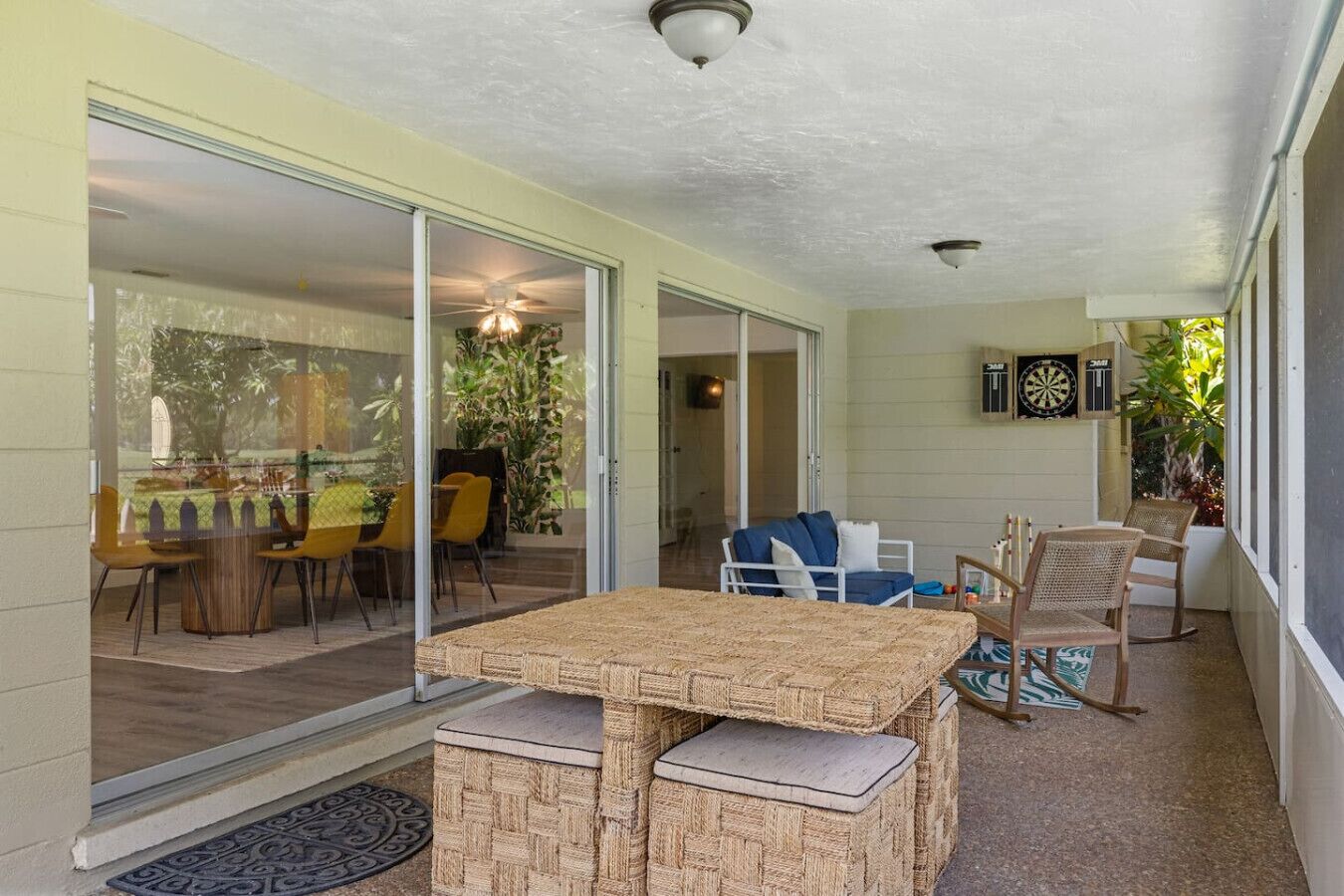A covered patio with a table and chairs, a sliding glass door leading to a dining area, and a ceiling fan.