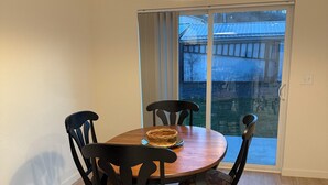 Un comedor con una mesa redonda de madera, seis sillas y una lámpara colgante.