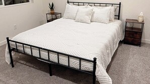 Un dormitorio con cama, mesita de noche, ventana y aire acondicionado.
