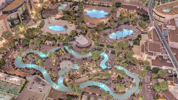 Vista aérea de un complejo turístico con varias piscinas, palmeras y zonas de estar al aire libre.