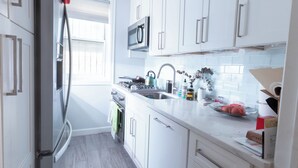 A modern kitchen with white cabinets, stainless steel appliances, and a window providing natural light.