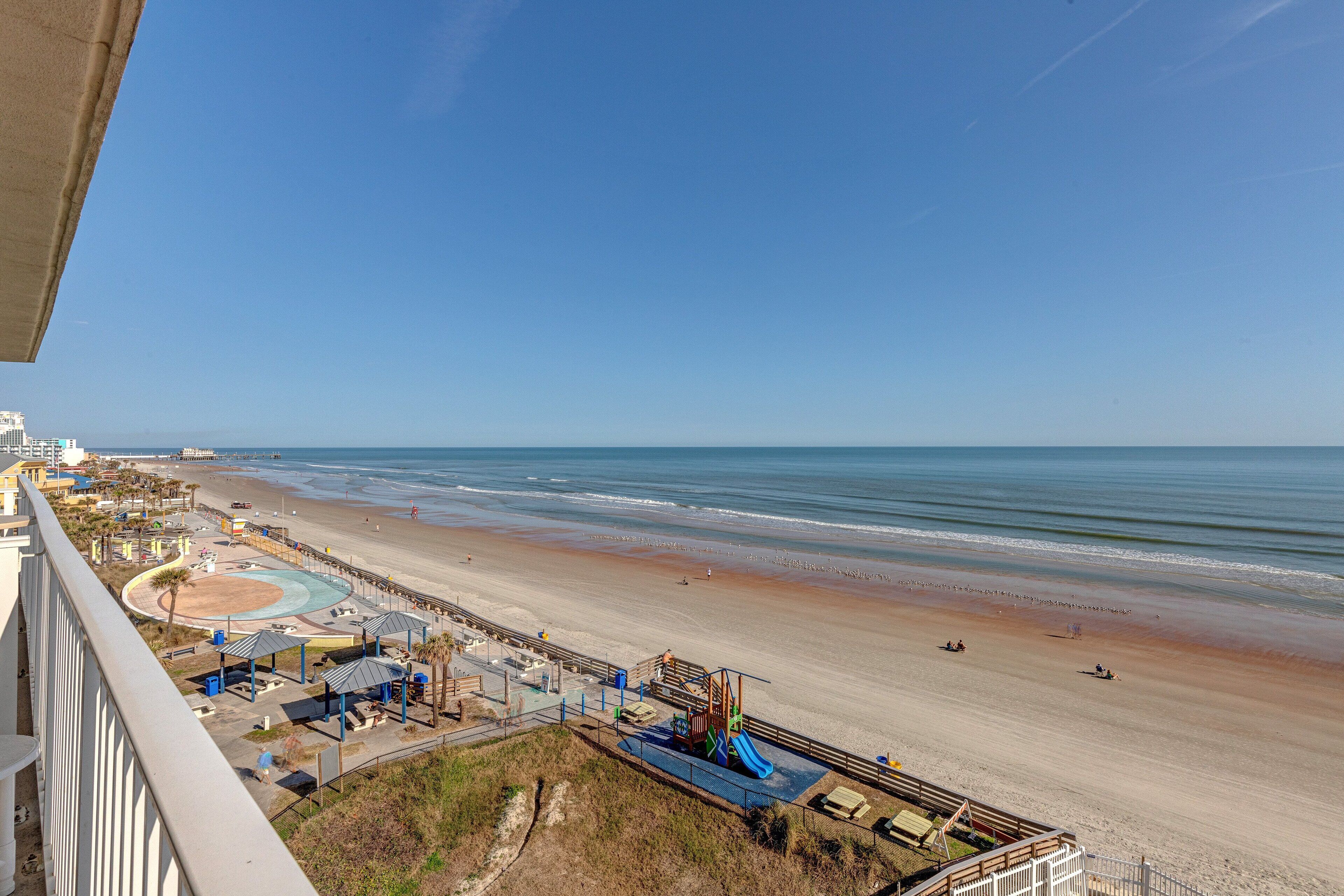 A beach view with a playground, a sandy beach, and a clear blue sky.