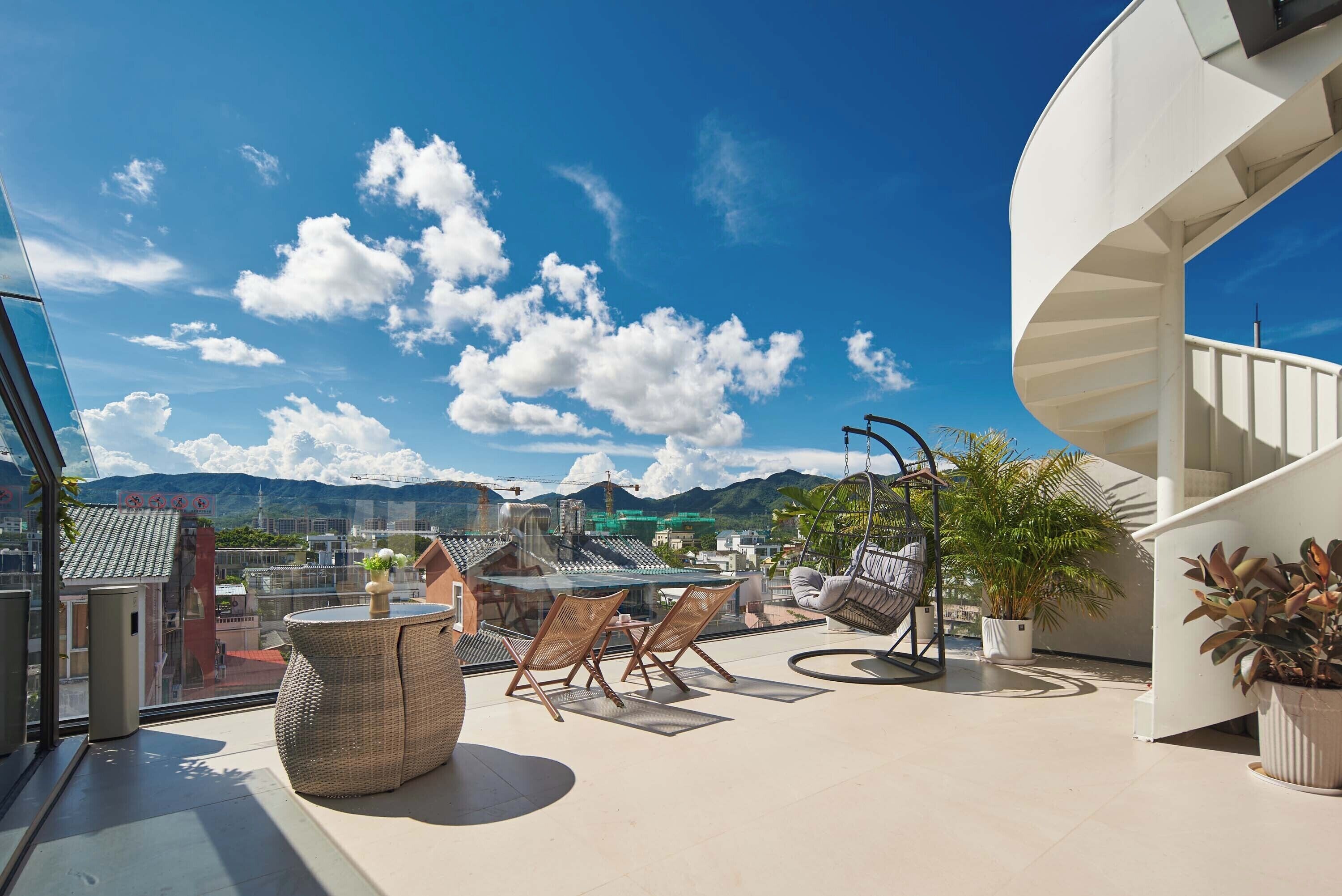 Una terraza en la azotea con muebles de mimbre, un sillón colgante y plantas en macetas.