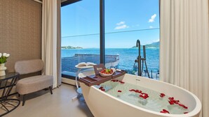 A modern bathroom with a large bathtub, a dining area with a table and chairs, and a view of the sea through large windows. - Santa Monica Seaview Vacation Home (Shenzhen)