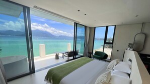 A modern hotel room with a large bed, a sitting area with a view of the sea, and a bathroom with a bathtub. - Santa Monica Seaview Vacation Home (Shenzhen)