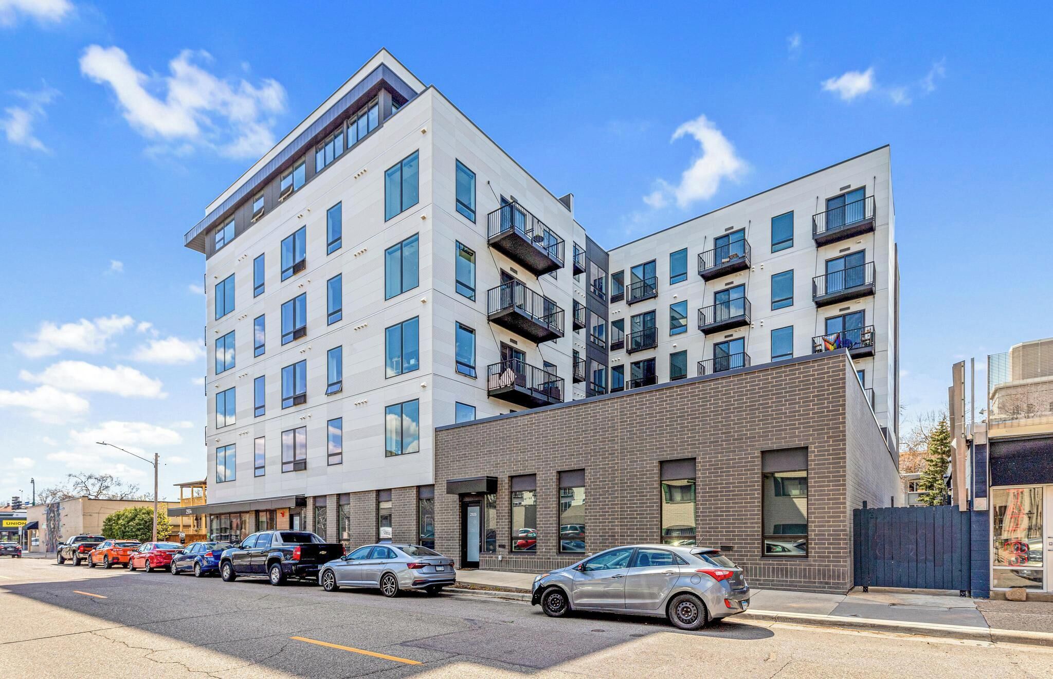 A modern multi-story building with a mix of residential and commercial spaces, featuring balconies and large windows.