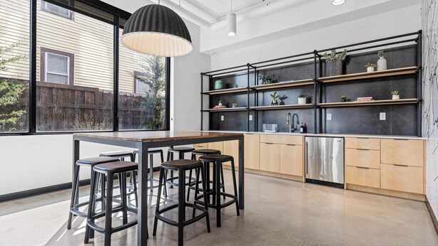 Eine moderne Küche mit Barbereich, großen Fenstern und Blick ins Freie.