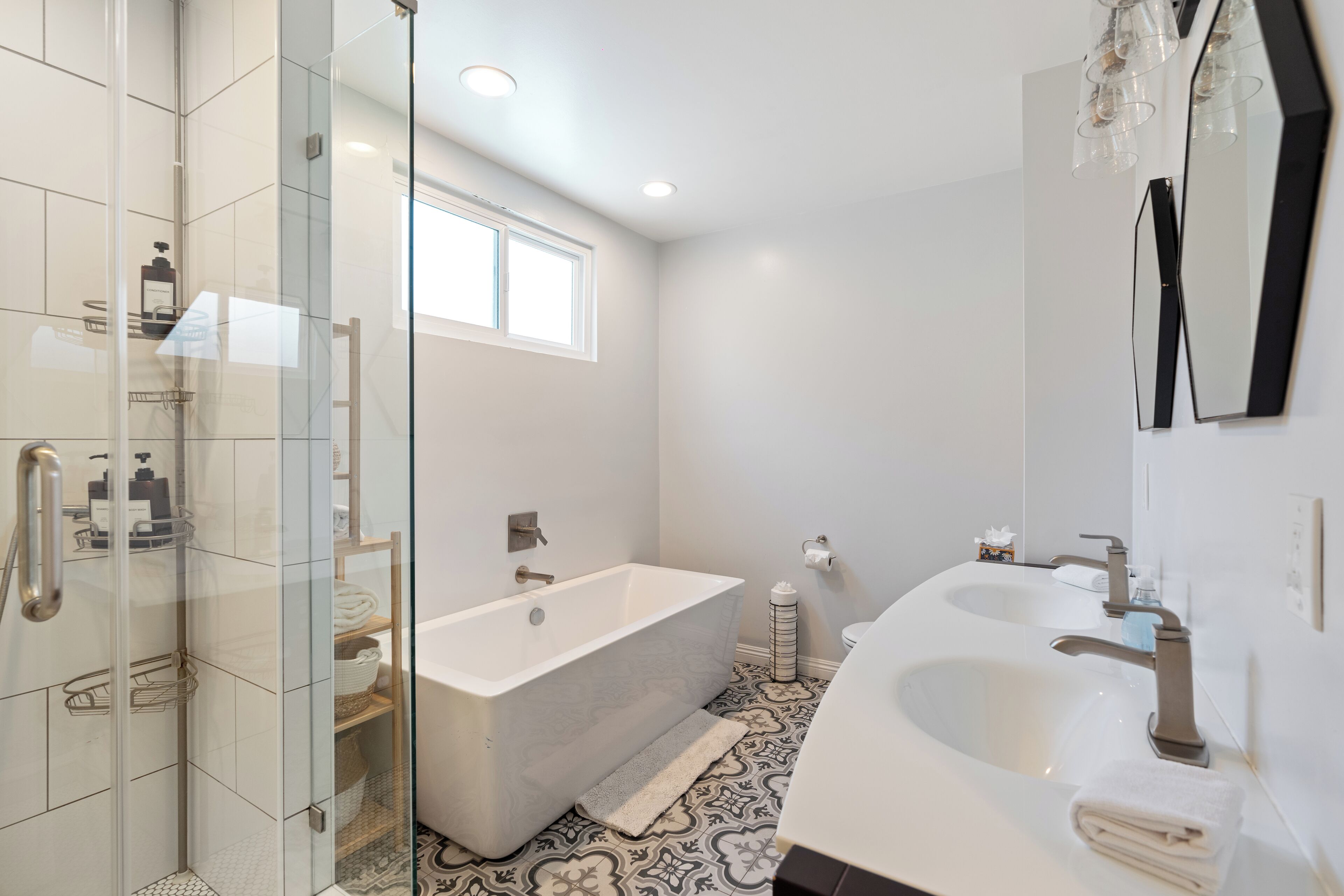 Ein modernes Badezimmer mit einer gläsernen Dusche, einer freistehenden Badewanne und einem Doppelwaschtisch.
