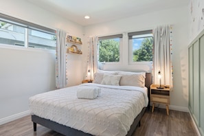 A bedroom with a bed, two bedside tables, a nightstand, and a window with curtains. - Bright Spacious Home With Office, BBQ & Backyard (Los Angeles)