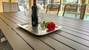 Ein Tisch mit einem Tablett, das eine Weinflasche, zwei Weingläser und eine rote Rose trägt.