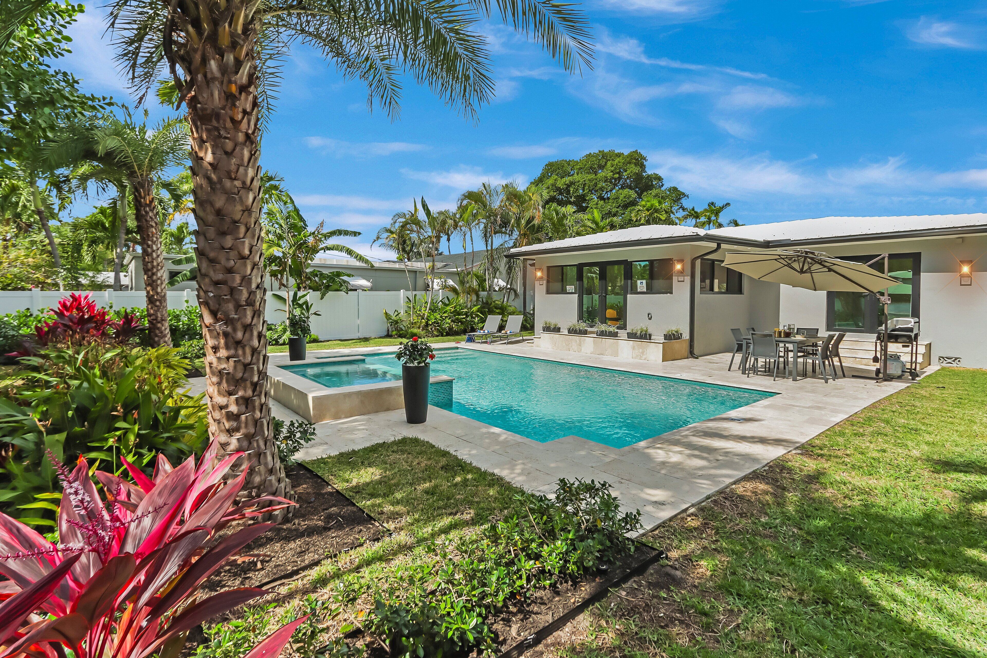 A modern house with a swimming pool, patio furniture, and lush greenery.
