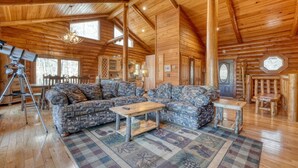 A log cabin interior with a large L-shaped sofa, a dining table, and a telescope. -  Acorn Abbey - Lakeside Retreat w/3BRs, spring on the water! (Murphy)