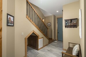 A staircase with wooden steps and a handrail, leading to a door with a blue frame. - Luxury 4 BR Mountain Escape: Views, Hot Tub & Pool Table (Banner Elk)