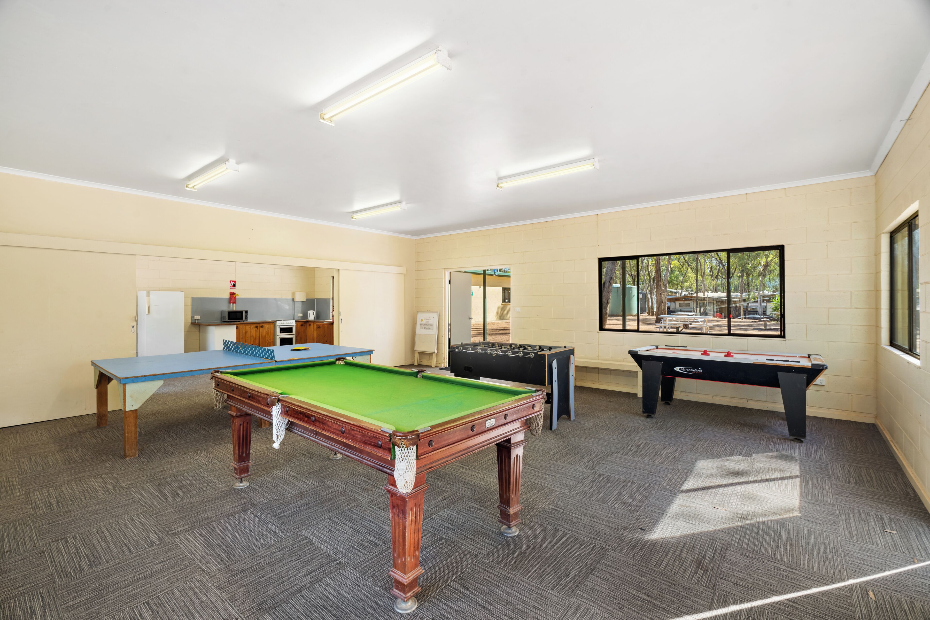 A room with a pool table, foosball table, and a ping pong table.