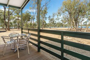 A covered outdoor area with a table and chairs, surrounded by trees and a view of a body of water. - Tiny Away Stay – Laanecoorie Lakeside (Laanecoorie)