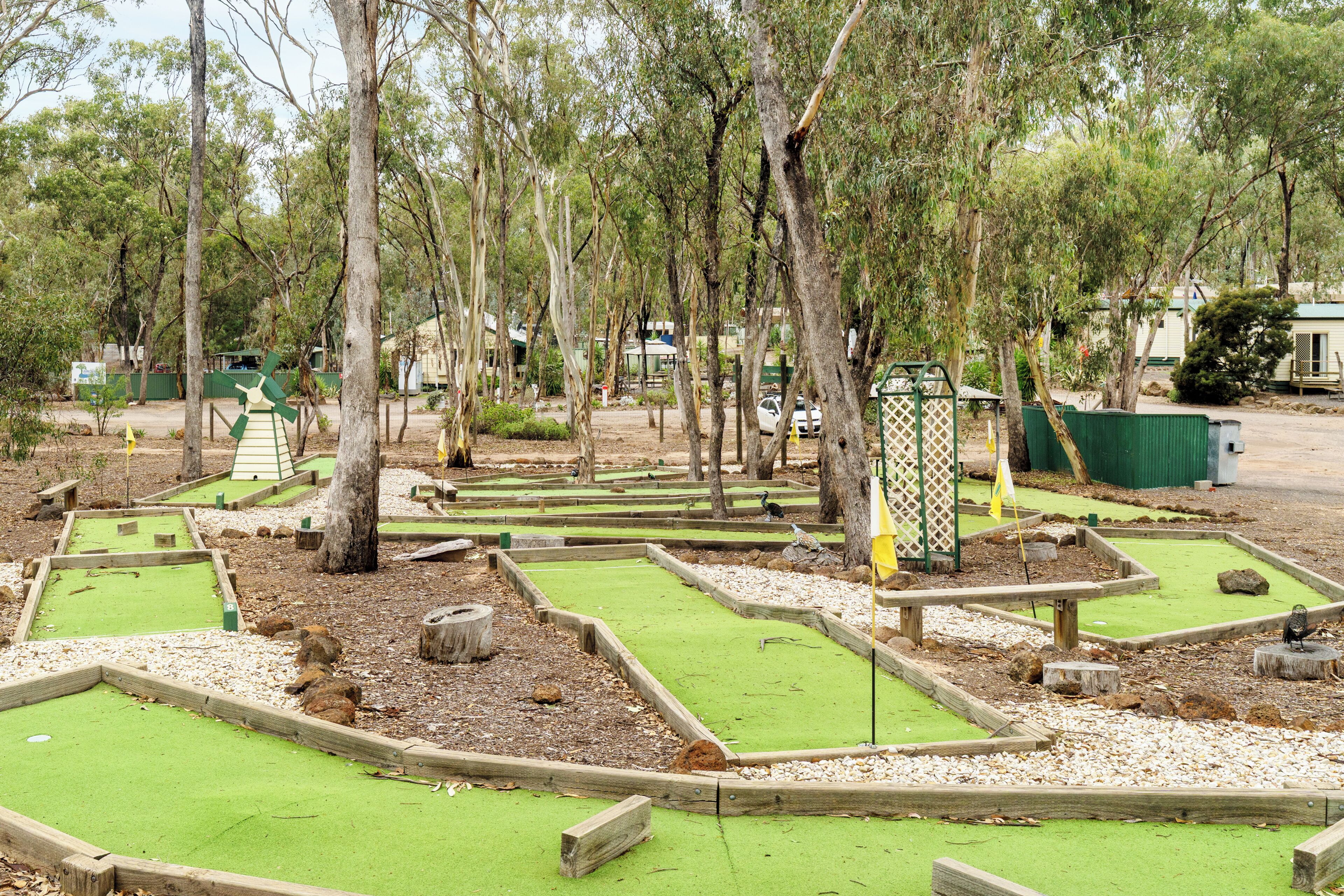 Un campo de mini golf con búnkeres de madera y césped artificial verde.