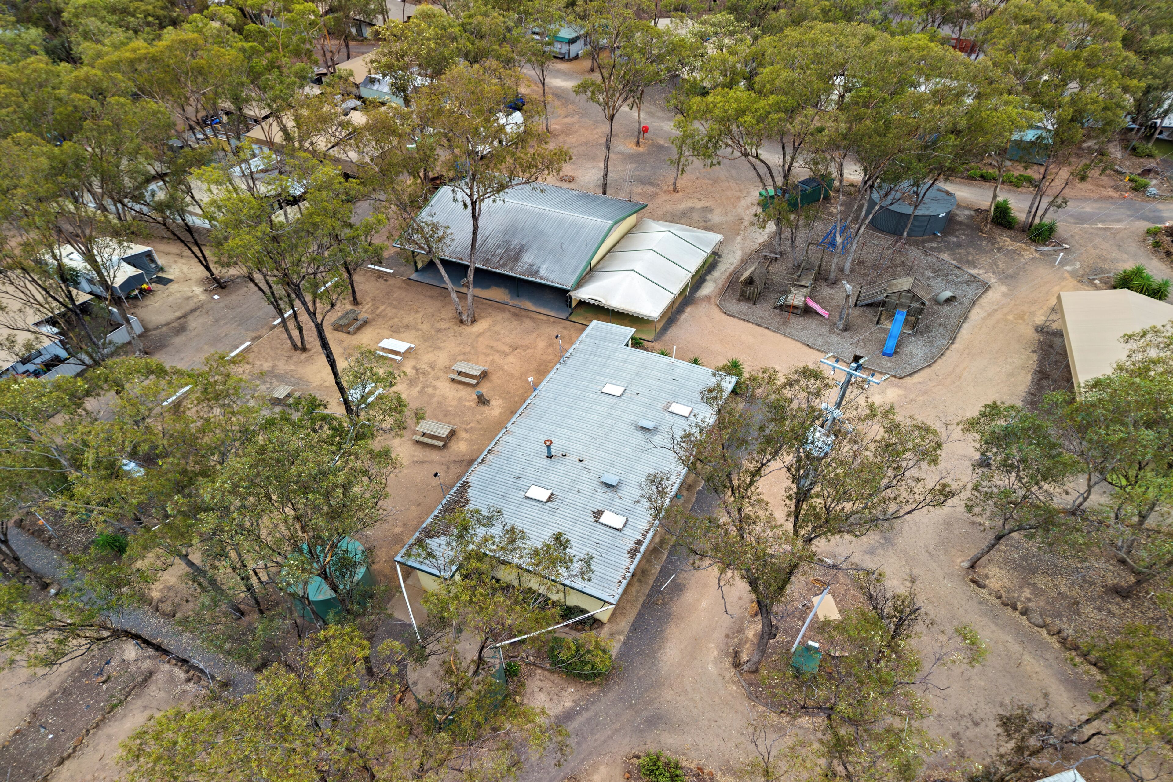 An aerial view of a campsite with tents, a covered area, and trees.