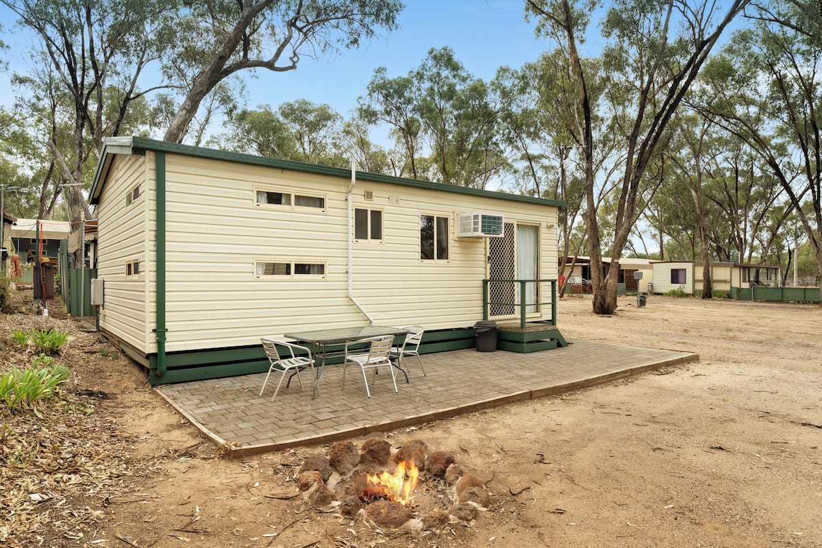A mobile home with a patio area, a fire pit, and a small table with chairs.