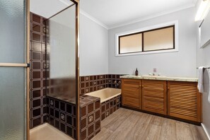 A bathroom with a bathtub, a shower, a vanity with a mirror, and a window above the mirror. - Tiny Away Stay – Laanecoorie Lakeside (Laanecoorie)
