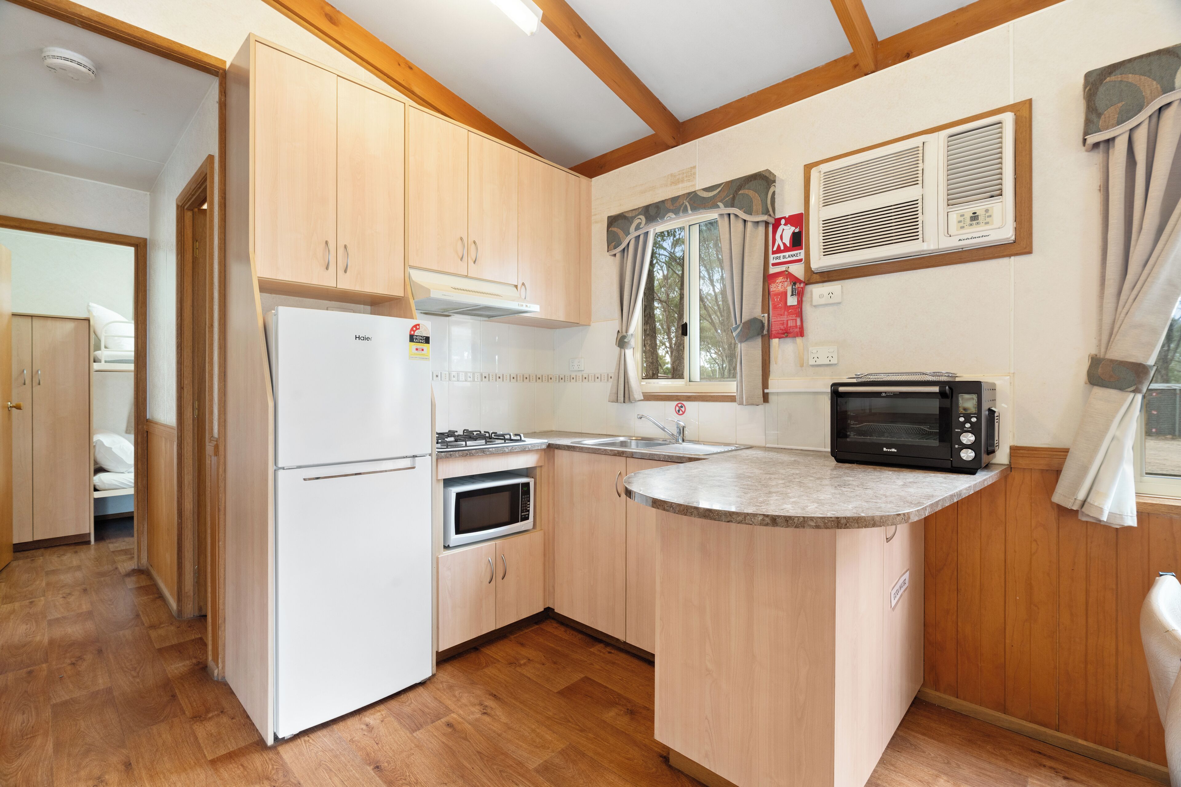 A compact kitchen with a refrigerator, microwave, stove, and a small sink.