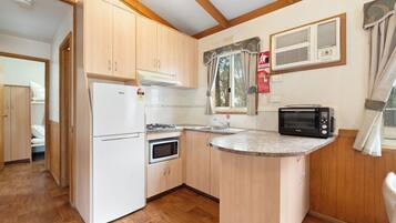 A compact kitchen with a refrigerator, microwave, stove, and a small sink.