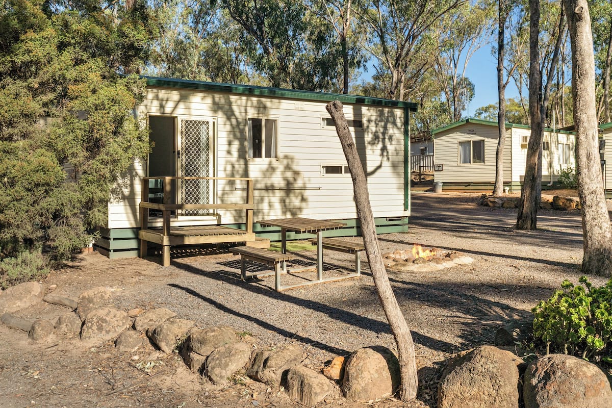 A mobile home with a porch, a picnic table, and a small garden area.