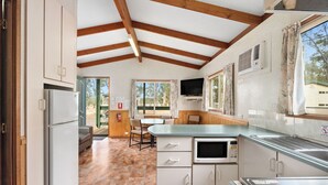 A kitchen with a built-in microwave, a stove, and a large window. - Tiny Away Stay – Laanecoorie Lakeside (Laanecoorie)