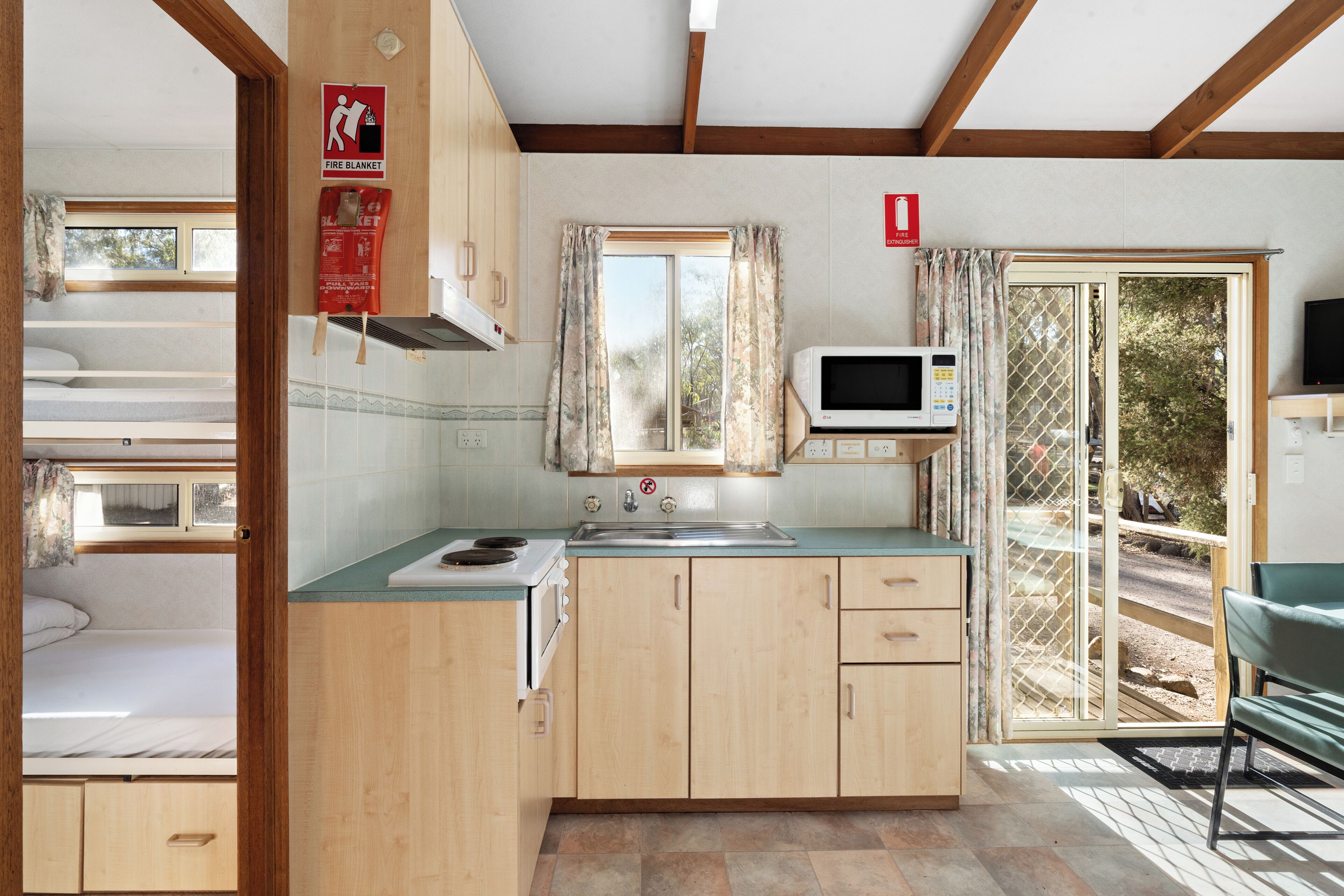 A compact kitchen with a microwave, sink, and wooden cabinets.