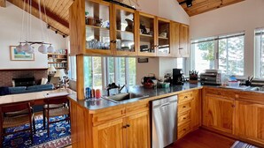 A spacious kitchen with wooden cabinets, a built-in dishwasher, and large windows. - Mid-coast Dream- Beautiful Oceanfront home with spectacular views! (St. George)