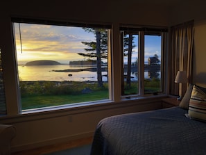 Ein Schlafzimmer mit einem großen Fenster, das Blick auf einen See und einen Wald bietet.