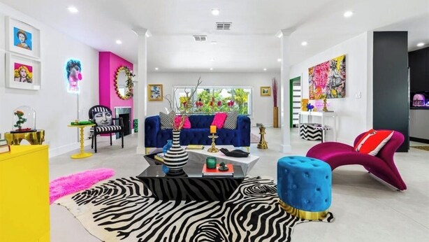 A modern living room with a blue sofa, colorful artwork, and a zebra-patterned rug.