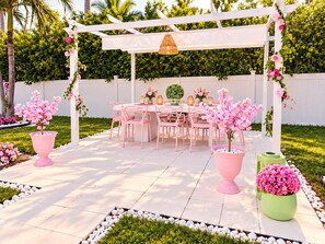 An outdoor patio with a white pergola, pink chairs, and a table set for dining. - Party villa. Steps to Beach. Cruise port. Pier 66 (Fort Lauderdale)