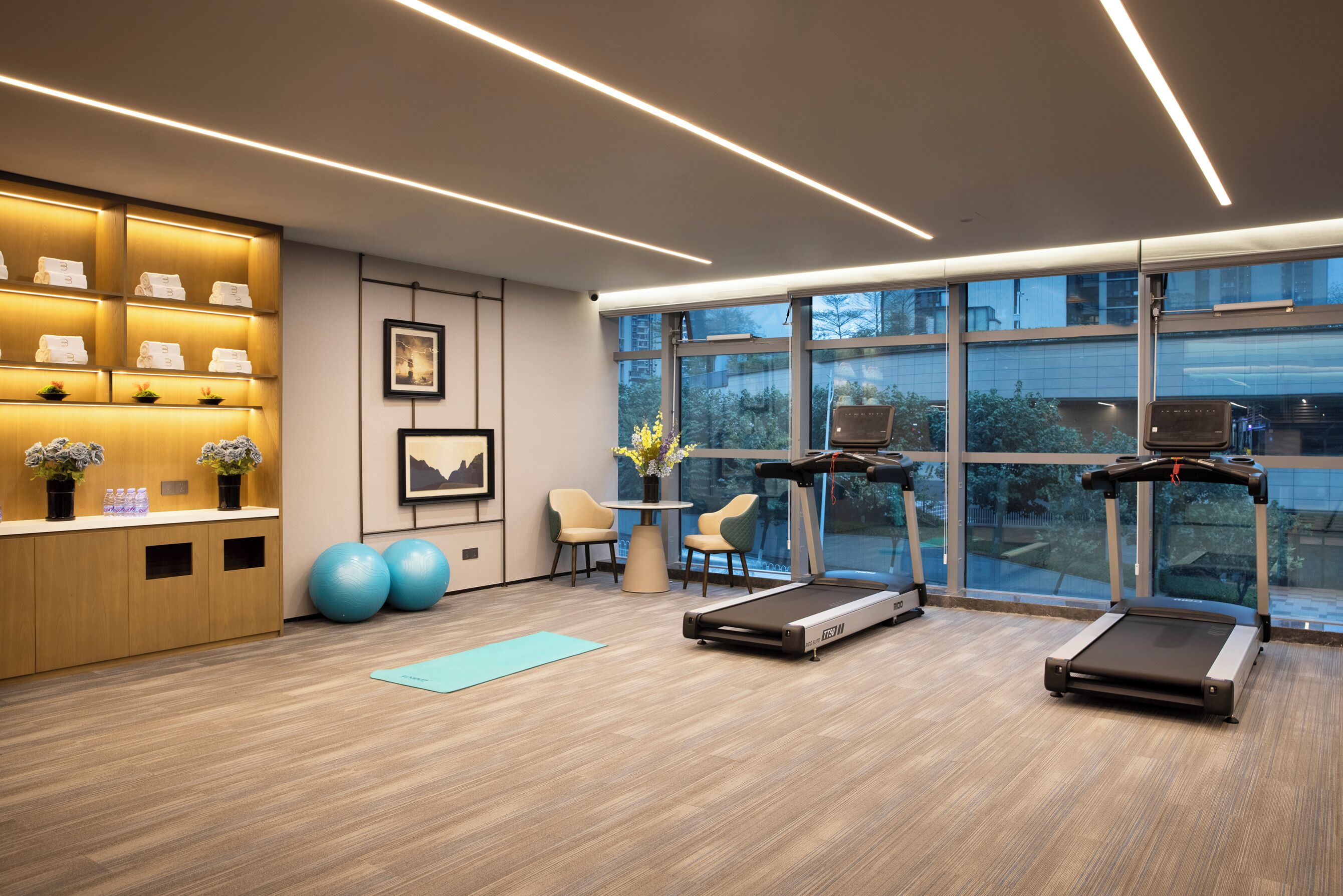 A modern gym with treadmills, exercise balls, and a reception area with a desk and chairs.