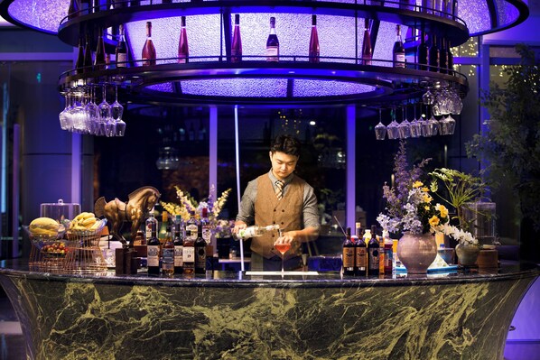 A bar area with a marble countertop, bottles, glasses, and a decorative horse statue. - Buddy Feely Hotel (Guangzhou)