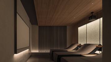 A modern spa room with two massage tables, a wooden ceiling, and a large window with blinds.