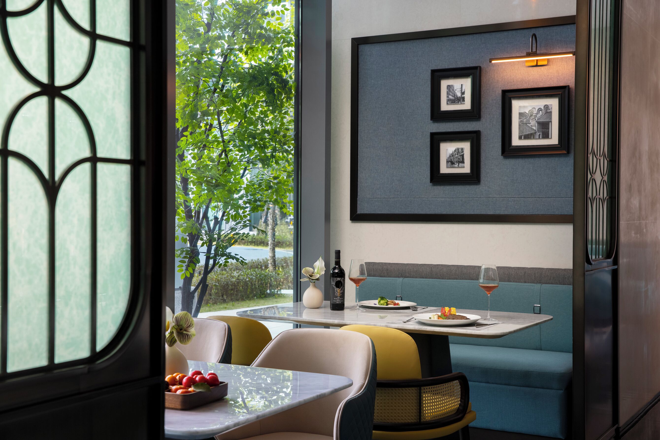 A dining area with a table, chairs, a bench, and a wall with framed pictures.