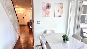 Ein Essbereich mit einem Marmortisch, weißen Stühlen und zwei abstrakten floralen Gemälden an der Wand.