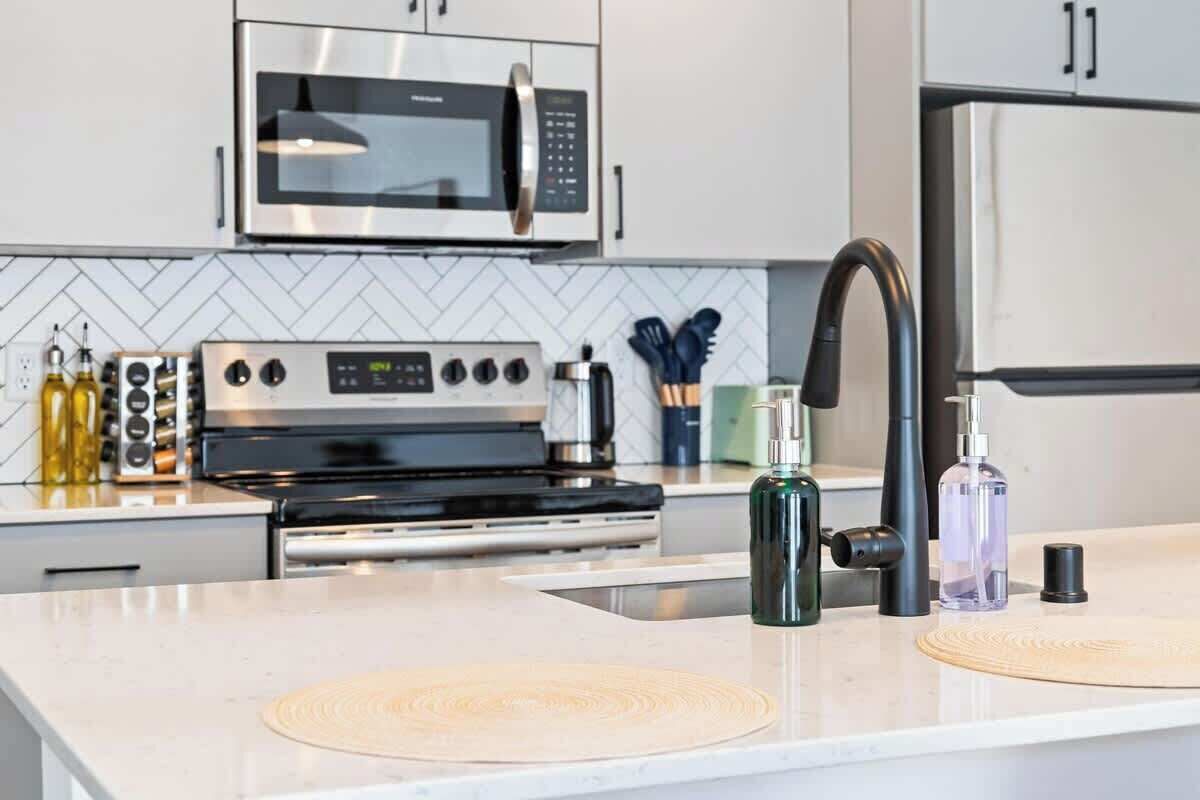Una cocina moderna con electrodomésticos de acero inoxidable, microondas, horno y un lavabo con grifo.