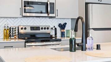 Una cocina moderna con electrodomésticos de acero inoxidable, microondas, horno y un lavabo con grifo.